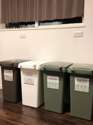 four trash cans lined up against a wall at Tanuki Shinjuku in Tokyo