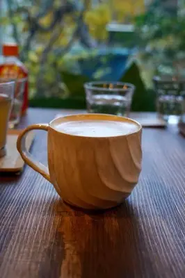 a cup of coffee sitting on a wooden table at [空港直接アクセス] JR山手線日暮里駅徒歩8分アパートメント/千駄木ハウス in Tokyo