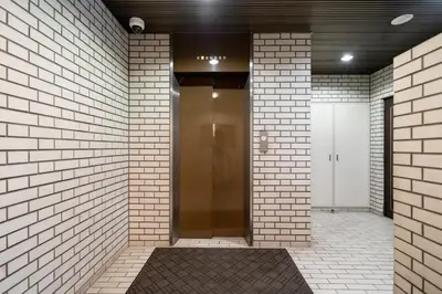 a hallway with a gold elevator in a brick wall at \u8d64\u5742\u516d\u672c\u6728\u30a8\u30ea\u30a2\u3000\u30de\u30f3\u30b9\u30ea\u30fc\u30de\u30f3\u30b7\u30e7\u30f3 in Tokyo