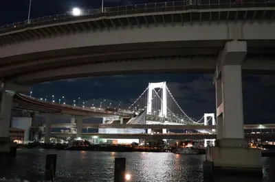 a bridge over the water at night with at \u99c5\u5f92\u6b694\u5206 \u90fd\u5fc3\u306e\u5e83\u3005\u7a7a\u9593 \u5404\u968e\u8cb8\u5207 \u9280\u5ea7 \u304a\u53f0\u5834 \u8c4a\u6d32\u3059\u3050 \u7530\u753a \u4e09\u7530\u99c5\u3082\u5229\u7528\u53ef in Tokyo