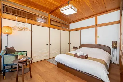 a bedroom with a bed and a table and a chair at Jujo house Direct to Shinjuku in Tokyo