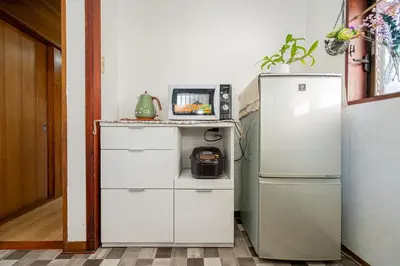 a kitchen with a white refrigerator and a table at Jujo house Direct to Shinjuku in Tokyo