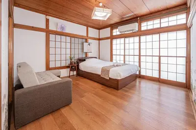 a bedroom with a bed and a couch and windows at Jujo house Direct to Shinjuku in Tokyo