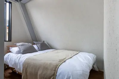 a bedroom with a bed with white sheets and pillows at \u8239\u5800\u6238\u5efa in Tokyo