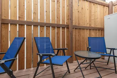 a patio with three chairs and a table in front of a fence at \u8239\u5800\u6238\u5efa in Tokyo