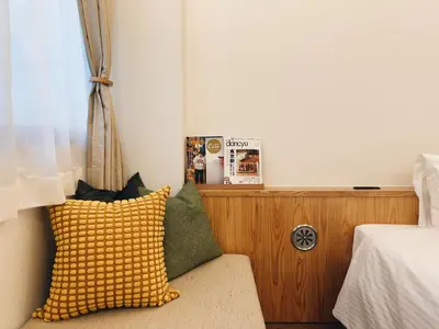 a bedroom with a couch with a yellow pillow at HERE.Tokyo in Tokyo
