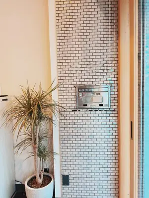 a plant in a pot next to a brick wall at HERE.Tokyo in Tokyo