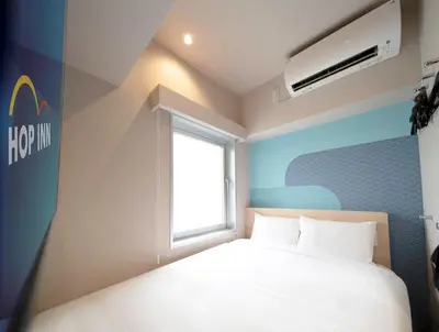 a small bedroom with a bed and a window at Hop Inn Tokyo Ueno in Tokyo