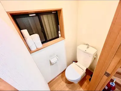 a bathroom with a toilet and a window with towels at \u5409\u5409\u306e\u5bb6 in Tokyo