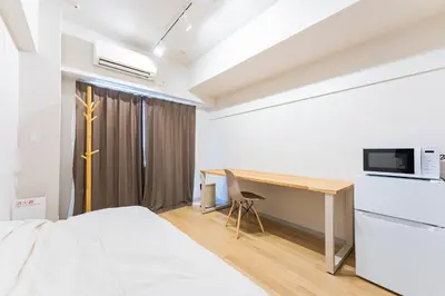 a bedroom with a bed and a desk with a microwave at unito residence IKEBUKURO in Tokyo
