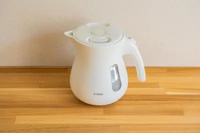 a white electric kettle sitting on a wooden floor at unito residence IKEBUKURO in Tokyo
