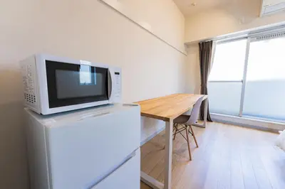 a small room with a table and a microwave at unito residence IKEBUKURO in Tokyo