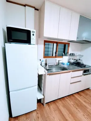 a kitchen with a white refrigerator and a sink at Oasis Aoto in Tokyo