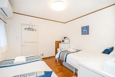 two beds in a room with white walls and wood floors at \u66255GWifi TokyoDome\u7687\u5c451km\u301c RoofGarden \u4e0a\u91ce\u79cb\u8449\u539f\u9280\u5ea7\u6771\u4eac2km\uff5e\u90fd\u5fc3 in Tokyo