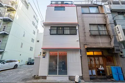 a building on a street with a woman standing in front of it at \u66255GWifi TokyoDome\u7687\u5c451km\u301c RoofGarden \u4e0a\u91ce\u79cb\u8449\u539f\u9280\u5ea7\u6771\u4eac2km\uff5e\u90fd\u5fc3 in Tokyo