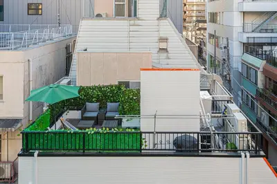 a balcony with an umbrella and chairs on a building at \u66255GWifi TokyoDome\u7687\u5c451km\u301c RoofGarden \u4e0a\u91ce\u79cb\u8449\u539f\u9280\u5ea7\u6771\u4eac2km\uff5e\u90fd\u5fc3 in Tokyo