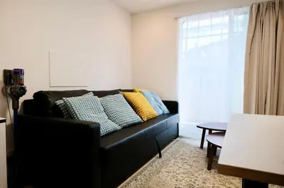 a black couch in a living room with a window at 100㎡ Cozy Villa in Shinjuku｜JR Shin-Ōkubo Sta. 7mins. in Tokyo