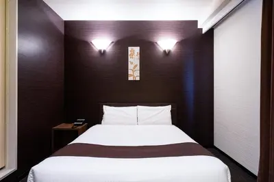a bedroom with a bed and two lights on the wall at Urvest Hotel Kamata in Tokyo