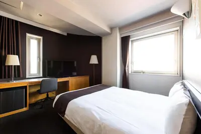 a hotel room with a bed and a desk and window at Urvest Hotel Kamata in Tokyo