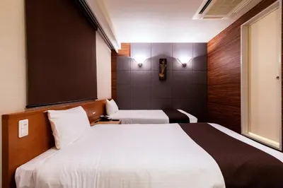 a hotel room with two beds and a window at Urvest Hotel Kamata in Tokyo