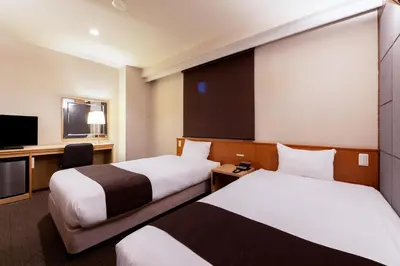 a hotel room with two beds and a television at Urvest Hotel Kamata in Tokyo