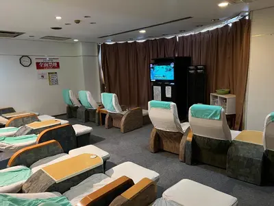 a waiting room with chairs and a video screen at 男性専用サウナ&カプセル Men Only Capsule Room & Sauna, Bathhouse ミナミ下北沢 Minami Shimokitazawa in Tokyo