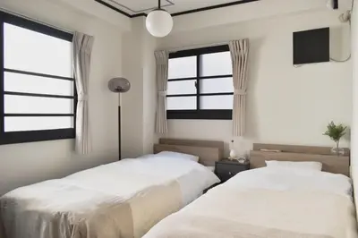 two beds in a bedroom with two windows at \u5ca1\u7530\u30d3\u30eb4\u968e in Tokyo