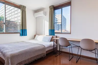 a bedroom with a bed and two chairs and windows at Residencial Voyan \u5357\u7802\u753a in Tokyo