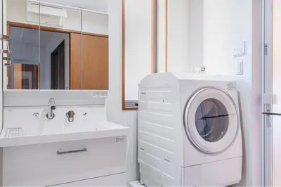 a white bathroom with a washing machine and a sink at Residencial Voyan \u5357\u7802\u753a in Tokyo