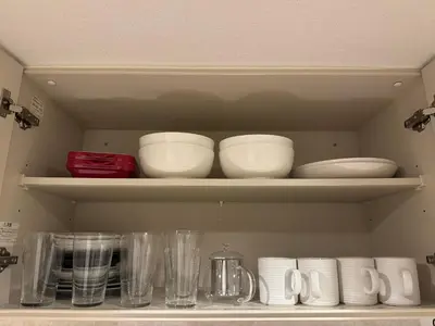 a kitchen shelf with bowls and plates and cups at waseda house in Tokyo