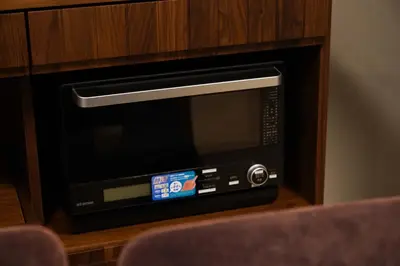 a microwave oven sitting in a wooden cabinet at Penthouse 1-bedroom flat in Hiroo Shibuya in Tokyo