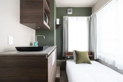 a bathroom with a sink and a bed in a room at THE CONTRAIL Ebisu in Tokyo
