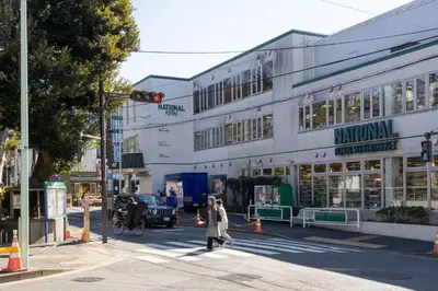 a woman crossing a street in front of a building at THE CONTRAIL Ebisu in Tokyo