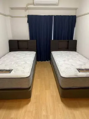 two twin beds in a room with blue curtains at G&R House 202　Shinjuku room in Tokyo