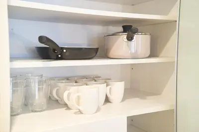 a shelf filled with white cups and a pot at FINOA Ikebukuro Sky Terrace Suite in Tokyo