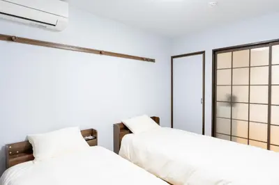 two beds in a room with white walls at \u96c0\u8272\u65b9\u5357 \u65b0\u5bbf\u99c5\u307e\u306714\u5206 \u6771\u4eac\u99c5\u307e\u306730\u5206 \u65b9\u5357\u753a\u5f92\u6b698\u5206 \u6700\u59272\u4eba \u6d17\u6fef\u6a5f \u30ad\u30c3\u30c1\u30f3 \u96fb\u5b50\u30ec\u30f3\u30b8 in Tokyo