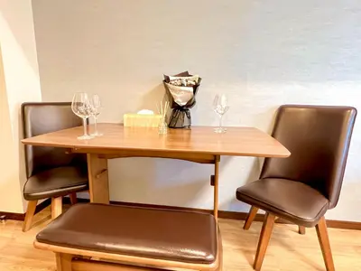 a wooden table with two chairs and wine glasses at East Ikebukuro Living&Bed Sunshine City in Tokyo