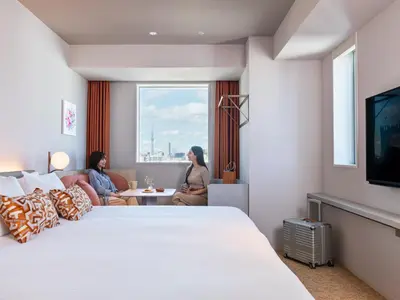 two women sitting in a hotel room with a large bed at Mitsui Garden Hotel Ginza Tsukiji in Tokyo