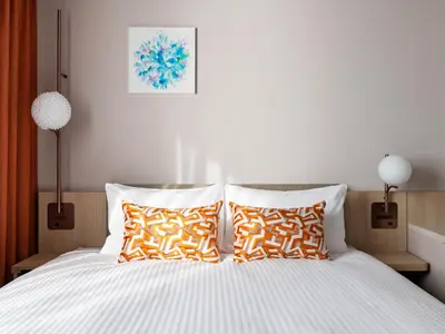 a bedroom with a bed with orange and white pillows at Mitsui Garden Hotel Ginza Tsukiji in Tokyo