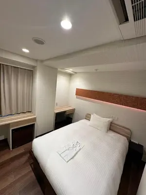 a bedroom with a large bed with white sheets at ELE Hotel \u6771\u65e5\u672c\u6a4b in Tokyo