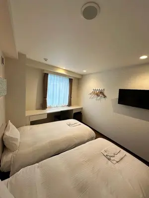 a bedroom with two beds and a flat screen tv at ELE Hotel \u6771\u65e5\u672c\u6a4b in Tokyo