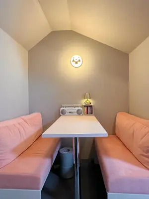 a room with two beds and a table and a clock at lobby, tateishi - Sauna & Stay in Tokyo