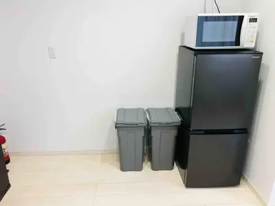 a microwave on top of a refrigerator next to two trash cans at \u30a2\u30f3\u30c9\u30b9\u30c6\u30a4\u5cf6\u5c3b5\u4e01\u76ee in Tokyo