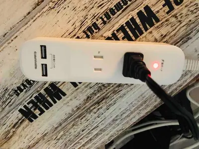a cell phone with a charging cord plugged into it at \u30a2\u30f3\u30c9\u30b9\u30c6\u30a4\u5cf6\u5c3b5\u4e01\u76ee in Tokyo