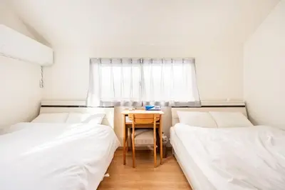 a room with two beds and a table and a window at \u30a2\u30f3\u30c9\u30b9\u30c6\u30a4\u5357\u9577\u5d0e5\u4e01\u76ee in Tokyo