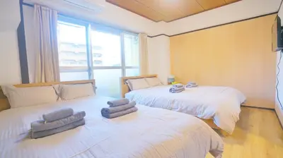 a bedroom with two beds and a large window at CowCow Hotel Shinjuku in Tokyo