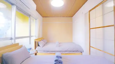 a small room with two beds and a window at CowCow Hotel Shinjuku in Tokyo
