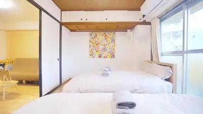 two beds in a room with a window at CowCow Hotel Shinjuku in Tokyo