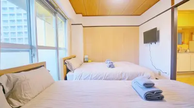a bedroom with two beds and a tv on the wall at CowCow Hotel Shinjuku in Tokyo