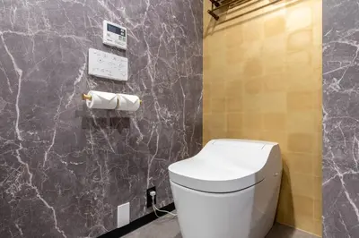 a bathroom with a white toilet and a marble wall at NEXUS HOTEL Gotanda in Tokyo